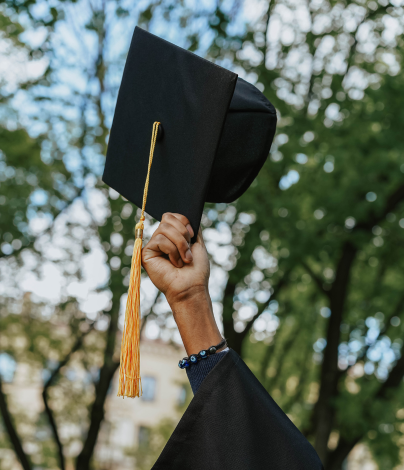 Student holding graduation cap in air